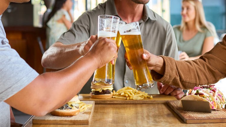 Drei Männer stoßen mit Bier an - auch bei der Berg Brauerei in Ehingen boomt das Geschäft mit alkoholfreiem Bier. (Symbolbild)