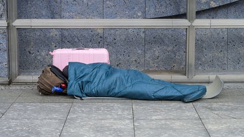 Eine obdachlose Person schläft auf dem Boden. (Symbolbild)
